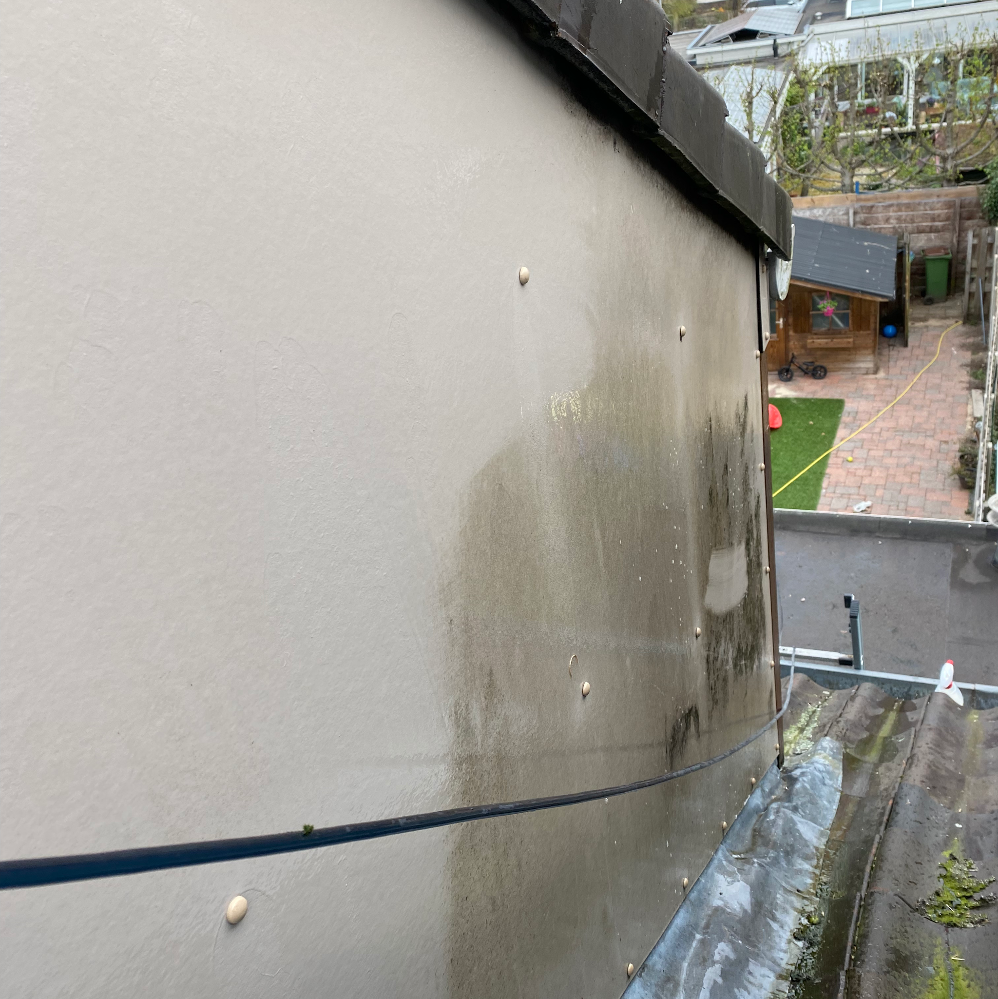 Lichte gevelplaat met groene strepen boven een plat dak